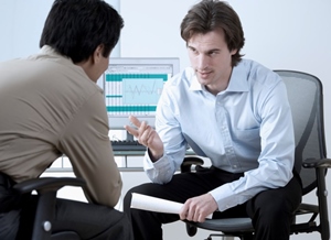 Two men learning forward and engaged in an intense conversion. Giving Performance Feedback