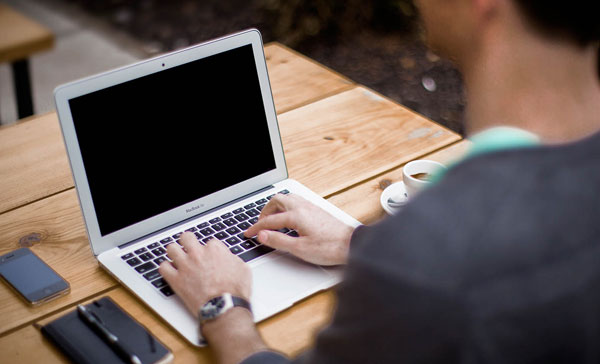 Partly obscured man typing on a Laptop. Using Email Effectively