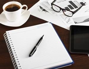 A notepad and pen with a cup of coffee