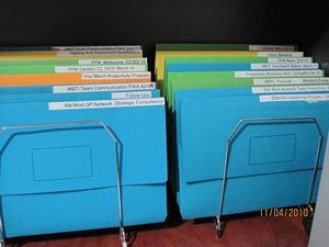 Coloured files stored in vertical holder on desk