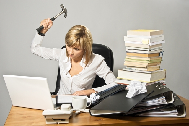 Angry business lady hitting a laptop with a hammer.