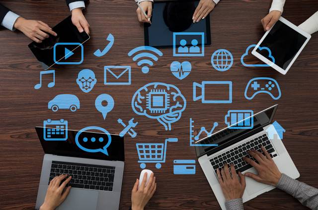 Laptops, Tablets in a circle on a desk with hands typing. Digital Productivity Tools